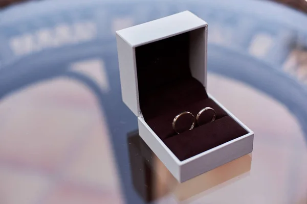 ガラスの上に横たわっている白い箱の中の2つの結婚指輪のクローズアップ — ストック写真