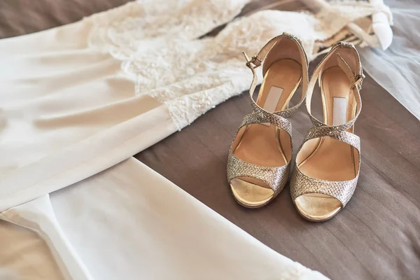 Vit elegant bröllopsklänning och skor liggande på sängen. — Stockfoto