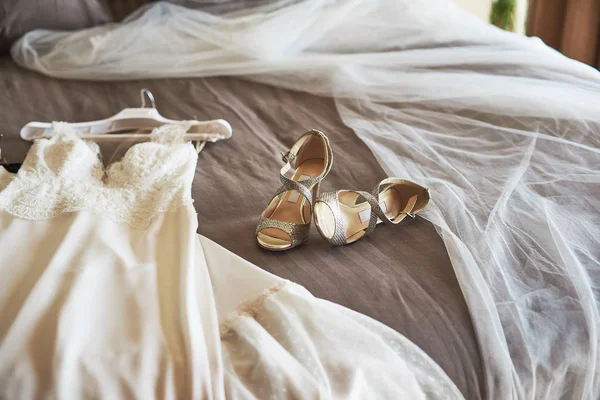 Robe de mariée élégante blanche, voile et chaussures allongées sur le lit . — Photo