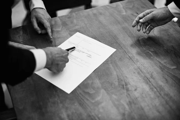 Monochrome image of groom signing marriage registration document