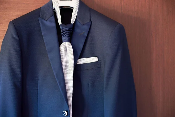 Primer plano del nuevo traje azul del novio y corbata colgando de una percha — Foto de Stock