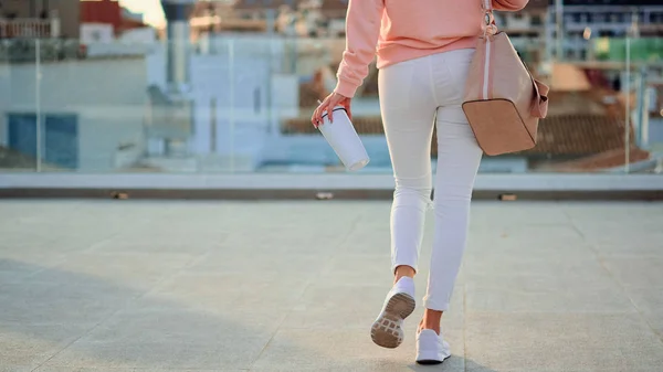 Close-up de jovem caminhando com uma caneca térmica branca nas mãos — Fotografia de Stock