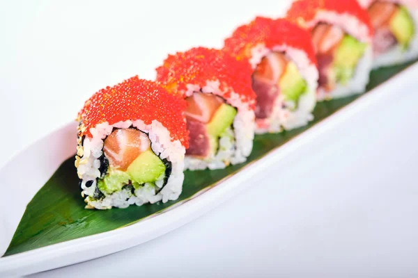 Uramaki sushi se sjíždí s červeným kaviárem, lososem a avokádem izolovanými na bílém — Stock fotografie