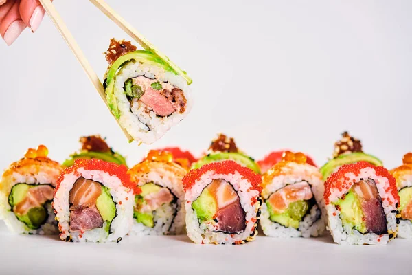 Primer plano de los rollos de sushi uramaki y rollo de mano femenina con palillos — Foto de Stock