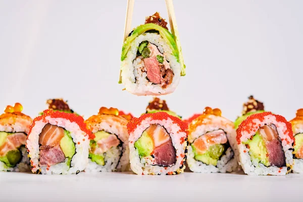 Primer plano de los rollos de sushi uramaki y rollo de mano femenina con palillos — Foto de Stock