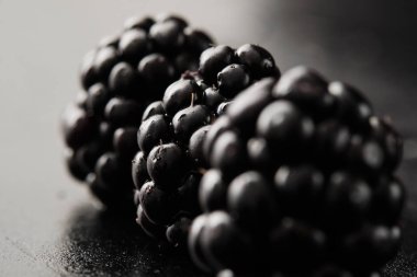 Karanlık arka planda izole üç böğürtlen yakın çekim.