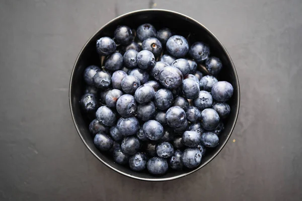Top view of freshly picked blueberries in black bowl on dark background — Stock Photo, Image