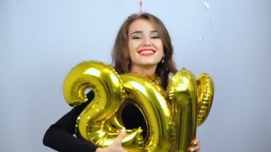 Altın 2019 balonları ve renkli konfetiler aşağı düşen tutan mutlu kız. Yavaş çekim. Yeni Yıl ve Noel konsepti.