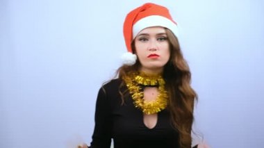 Siyah elbise ve kırmızı Noel Baba şapka renkli alışveriş çantaları beyaz arka plan üzerinde izole gösteren genç ciddi kadın. Black Friday, Noel veya Yeni Yıl konsepti. Yavaş çekim.