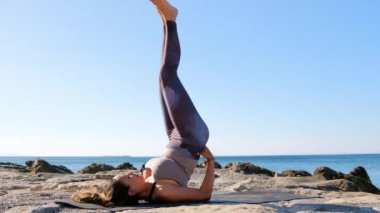 Genç ve çekici İspanyol kadın sahilde yoga yapıyor..