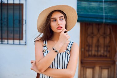 Sokakta yürüyen, saman şapkalı zarif bir kadının moda portresi..