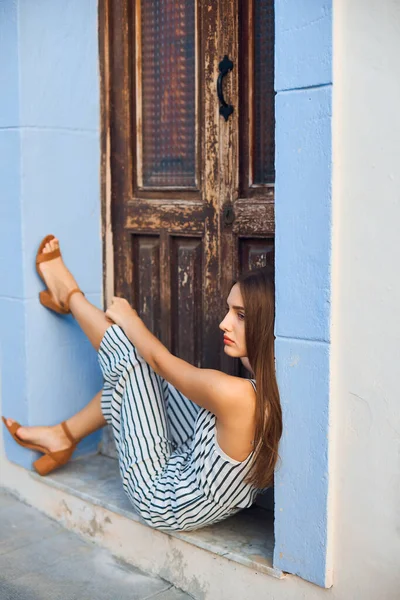 Mujer joven y elegante posando en la vieja puerta de madera en la calle . — Foto de Stock