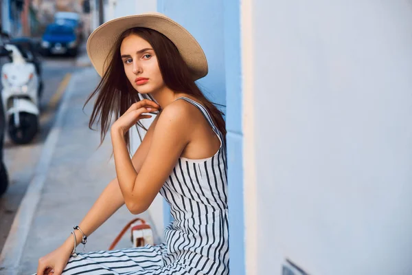 Retrato de mujer joven elegante en sombrero de paja sentado en la calle . —  Fotos de Stock