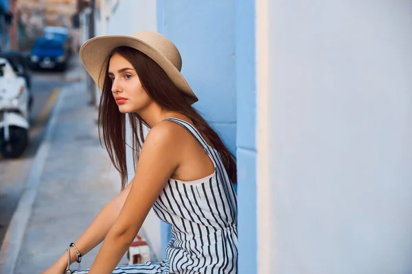 Retrato de mujer joven elegante en sombrero de paja sentado en la calle . —  Fotos de Stock