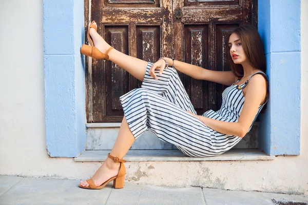 Молода стильна жінка позує в старому дерев'яному дверному отворі на вулиці . — стокове фото