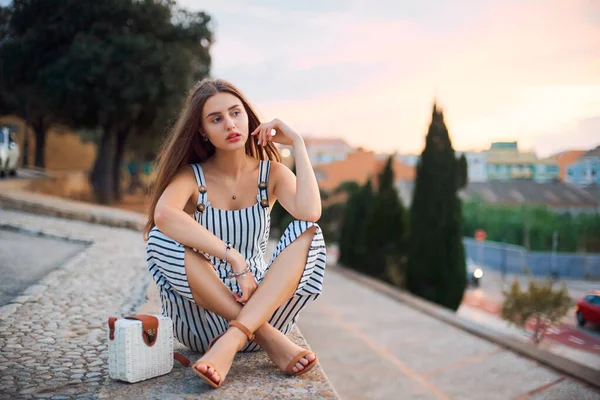 Jovem mulher descalça elegante posando na rua ao pôr do sol . — Fotografia de Stock