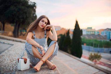 Gün batımında sokakta poz veren genç, zarif, çıplak ayaklı kadın..