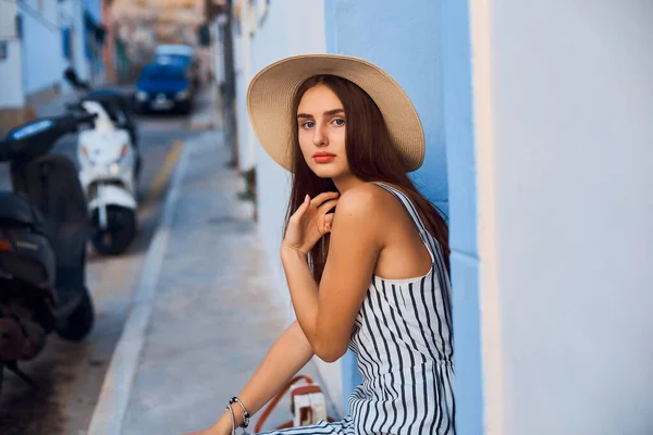 Retrato de mujer joven elegante en sombrero de paja sentado en la calle . —  Fotos de Stock