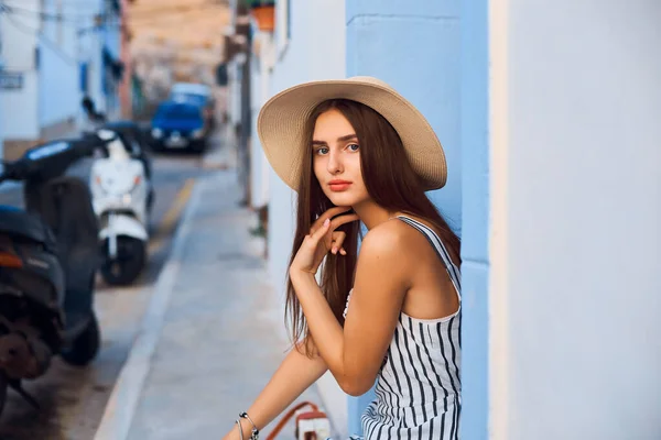 Retrato de mujer joven elegante en sombrero de paja sentado en la calle . —  Fotos de Stock