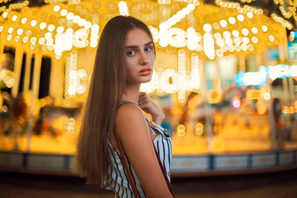 Jolie jeune femme sur fond de lumières de carrousel lumineux magiques . — Photo