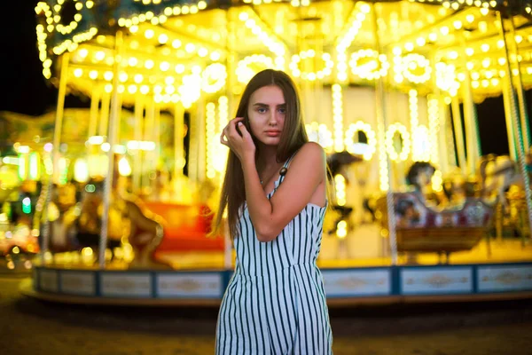 Mulher bonita contra o fundo de luzes de carrossel brilhantes mágicas . — Fotografia de Stock