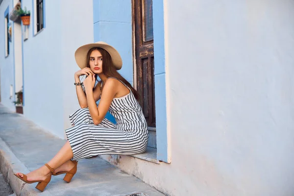 Retrato de moda de jovem mulher elegante em chapéu de palha sentado na rua . — Fotografia de Stock