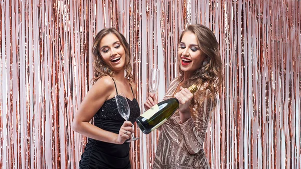 Twee mooie elegante vrouwen drinken champagne tegen sprankelende — Stockfoto