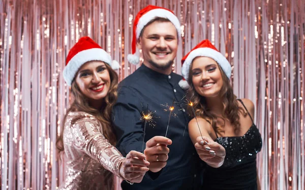 Jovem e mulheres desfrutando de Natal com faíscas nas mãos . — Fotografia de Stock