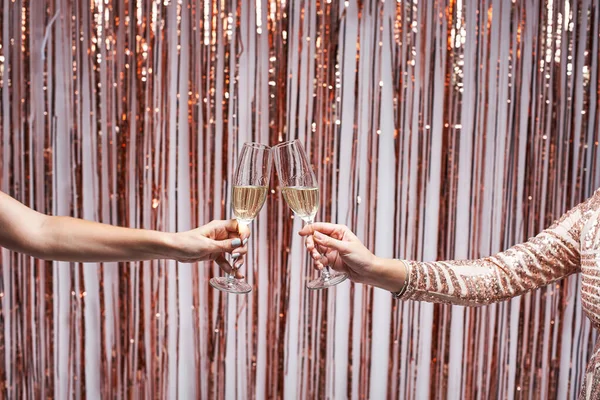 Close-up van twee vrouwelijke handen klinkende champagne glazen. — Stockfoto