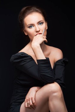 Koyu renk elbiseli güzel bir kız elinde bir sigara ve kuaför erkek elleriyle çerçeveye bakar.