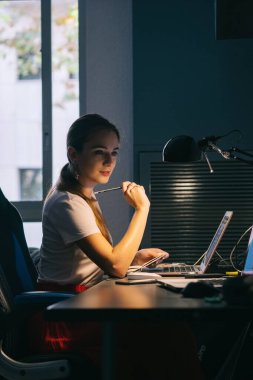 Kız bilgisayarın başında çalışıyor. Ofiste çalışmaya odaklanmış. Yeni bir fikir arıyor.