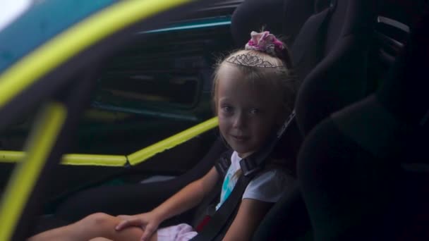 KIEV, Ucrania - 17 de agosto de 2018: Linda niña en la corona se sienta en un coche — Vídeo de stock
