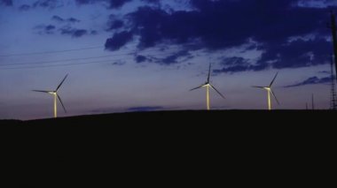 Gece karanlığında ufukta sırasında birkaç yel değirmenleri rüzgar enerjisi alanında