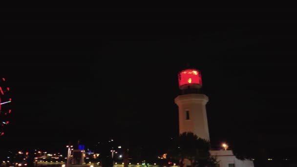 Night landscape of park with a lighthouse with palm trees and Ferris wheel — Stock Video