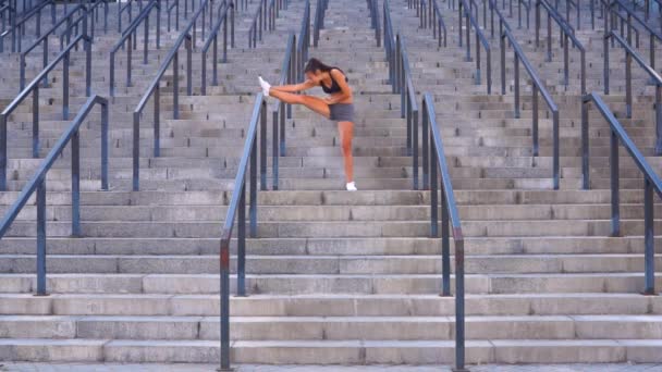Femeia tânără care face exerciții de fitness și exerciții de întindere pentru sănătate pe scările stadionului — Videoclip de stoc