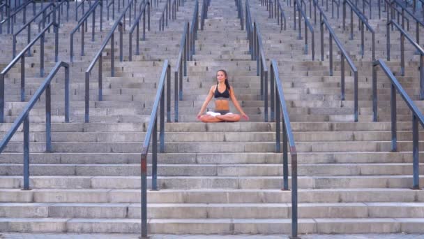 Chica joven haciendo yoga posición de loto en las escaleras al aire libre — Vídeos de Stock