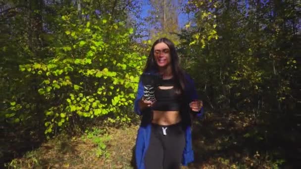 Brunett ung kvinna bloggare går i skogen och videoinspelning för vlog använder kameran slowmotion — Stockvideo