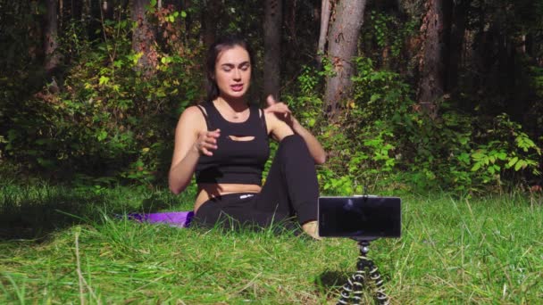 Ung brunett kvinna bloggare att göra sport övningar i soliga skog — Stockvideo