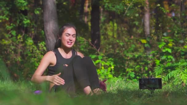 Jovem morena blogueira fazendo exercícios esportivos na floresta ensolarada câmera lenta — Vídeo de Stock