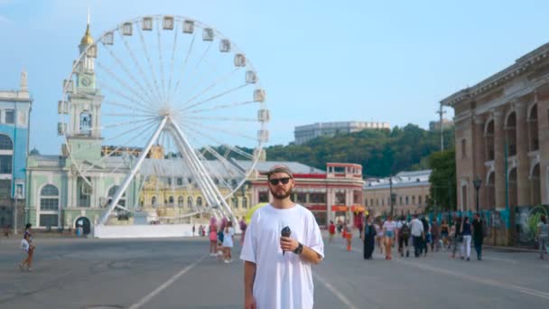 Kiev, Ukraina - 17 augusti 2018: Skäggiga killen håller black ice cream nära pariserhjul — Stockvideo