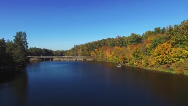 Vista aérea volando sobre el hermoso río de otoño con puente y bosque — Vídeo de stock