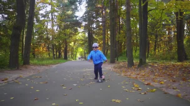 Kind op skateboard jongen rijden op skate buiten in herfst park — Stockvideo