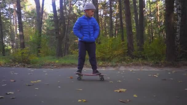 Niño en monopatín niño paseo en patín al aire libre en el parque de otoño — Vídeos de Stock