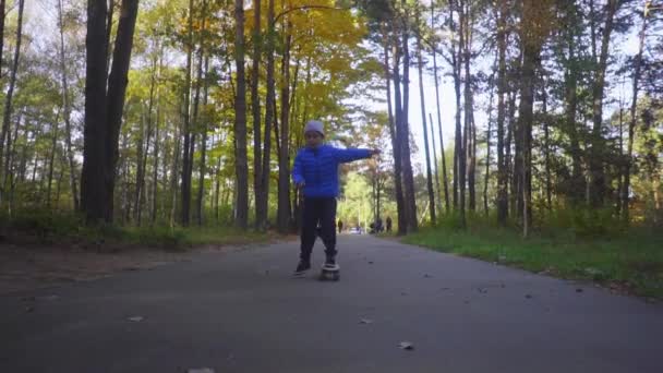 Skateboarder garçon enfant promenade sur le patin en plein air dans le parc d'automne 