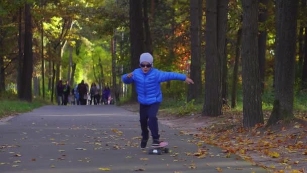 Skateboarder boy child ride on skate outdoor in autumn park — Stock Video