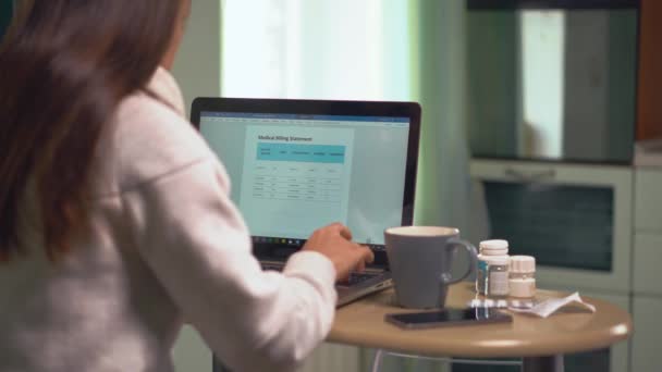 Femme regarde la facture médicale et le type de prix de la facture à la table sur ordinateur portable — Video