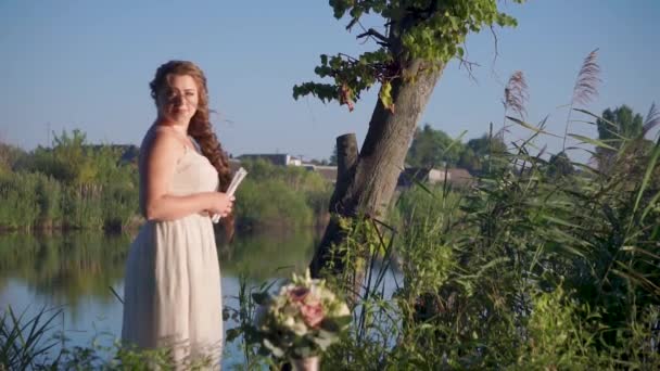 Joven mujer sonriente está esperando a su querido hombre a orillas del río historia de amor — Vídeo de stock