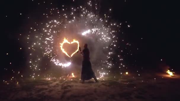 Uomo artista twist fuoco oggetti nelle sue mani fuoco scintillante spettacolo con cuore ardente su sfondo — Video Stock