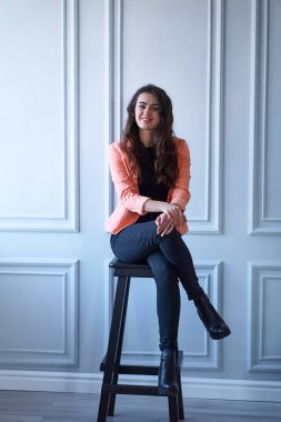 Sandalyede oturan şeftali ceketli çekici esmer kız portresi