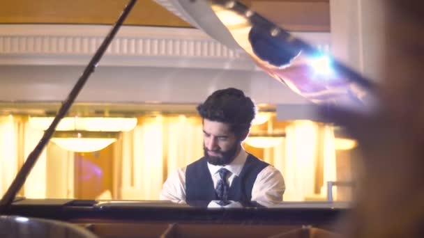 Κλείνω πάνω θέα του γενειοφόρος πιανίστας που παίζει το φορτεπιάνο απολαμβάνοντας βιρτουόζος μουσικής αντικατοπτρίζεται στην κάλυψη πιάνο — Αρχείο Βίντεο